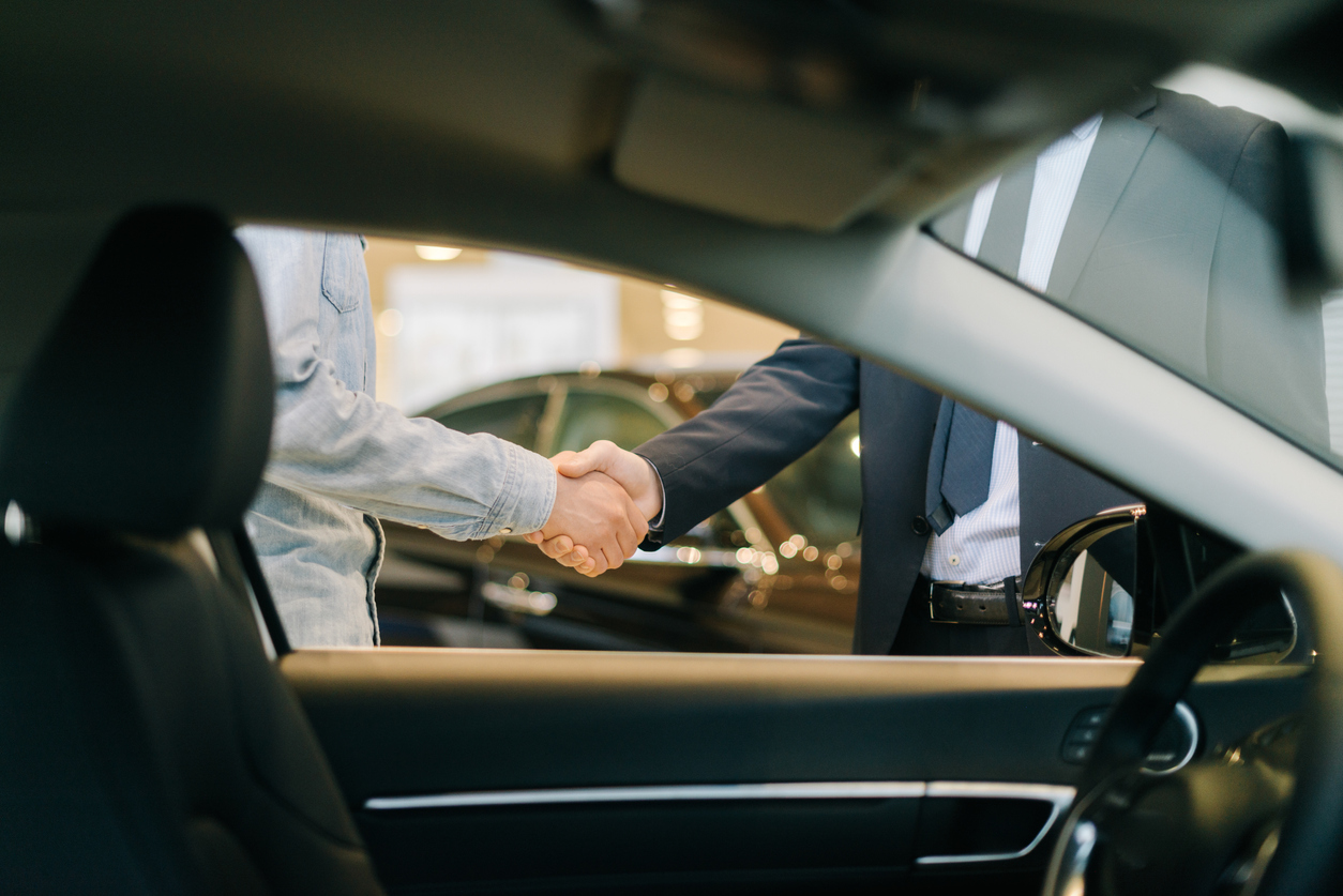 customer shaking hands with salesman in car dealership 1